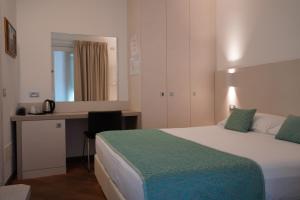 una camera con letto, scrivania e specchio di Hotel Ponti ad Angera