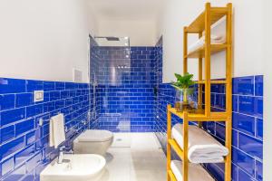 La salle de bains est pourvue de carrelage bleu, de toilettes et d'un lavabo. dans l'établissement Starguest Dante, à Naples