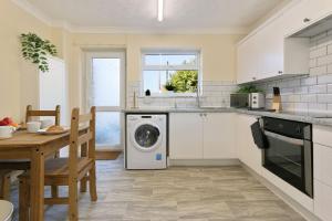 a kitchen with a washing machine and a table at ZSKstays! Comfortable home, nice area, free parking and large garden! in Hull