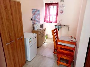 a small kitchen with a table and a white refrigerator at Lindo Guest house in Estcourt