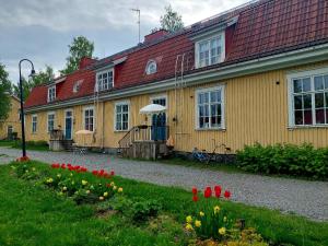 a yellow house with red roofs and flowers in front of it at Nostalginen residenssi Taika in Varkaus