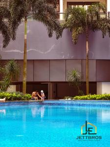 - une piscine en face d'un bâtiment avec des palmiers dans l'établissement R&F Princess Cove By JettBros Johor Bahru, à Johor Bahru