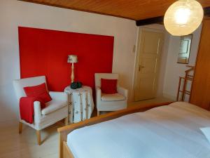 1 dormitorio con 2 sillas, 1 cama y pared roja en Haus am Bach, en Hallenberg