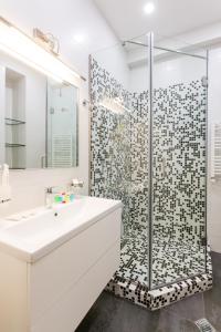 La salle de bains est pourvue d'une douche avec un lavabo blanc et une porte de douche en verre. dans l'établissement Comfy Home V, à Tbilissi