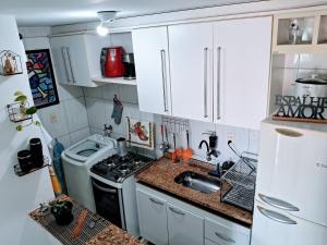 cocina con armarios blancos, fogones y fregadero en Solar do Pontal - Lindo Apartamento a 600m da praia, en Río de Janeiro