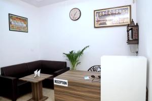 a living room with a table and a clock on the wall at Hotel Homeland Inn in Sirsa