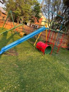un parque infantil con un tobogán azul en el césped en Soft petal en Pretoria