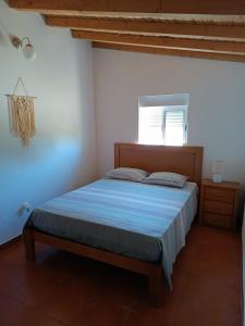 a bedroom with a bed with blue sheets and a window at Casas do Montinho in Melides
