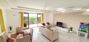 ein Wohnzimmer mit einem Sofa und einem TV in der Unterkunft Luxury 3br Ensuite Apt in Prestigious Nyali in Mombasa