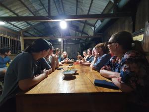 a group of people sitting around a wooden table at Ba Linh Homestay in Vĩnh Long