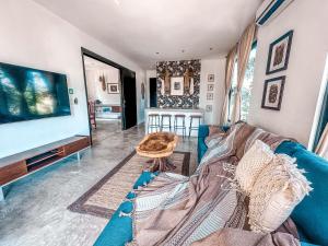 een woonkamer met een blauwe bank en een tv bij Naats Amigos Tulum in Tulum