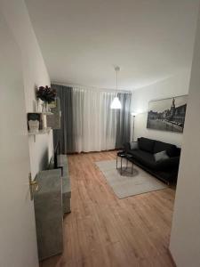 uma sala de estar com um sofá preto e pisos em madeira em Lichtung Appartement - *WLAN**Netflix**Stadion-Nah* em Leipzig