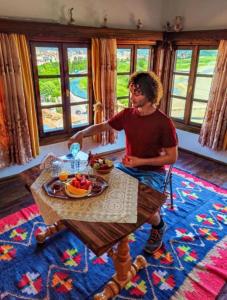 un homme assis à une table avec un bol de fruits dans l'établissement Guest House Mikel, à Berat