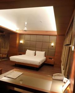 a bedroom with a bed and a desk at Hotel Cosmopolitan in Ahmedabad