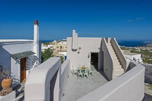 een wit huis met een trap en een tafel en de oceaan bij Pyrgos terracevilla in Pirgos