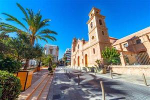 a building with a clock tower next to a street at Policarpo-centro in Torrevieja