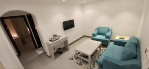 Zimmer mit 2 Stühlen, einem Tisch und einem TV in der Unterkunft فندق جرين ليف in Dschidda