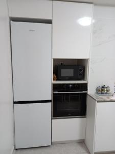 a white kitchen with a stove and a microwave at Policarpo-centro in Torrevieja