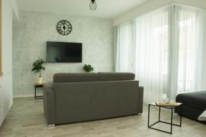 salon z kanapą i zegarem na ścianie w obiekcie Apartmán X28 w mieście Mikulov