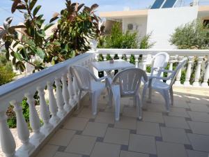 un patio con sillas blancas y una mesa en el balcón en Sunny Villa, en Ksamil