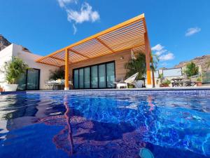 a swimming pool in front of a house at Villa de lujo con piscina climatizada in Mogán