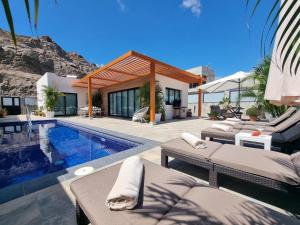 uma villa com uma piscina e uma casa em Villa de lujo con piscina climatizada em Mogán