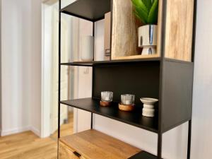a black book shelf with two cups on it at Luxury Style 2 Room Apartment by R&L in Centre in Leipzig +13 photos