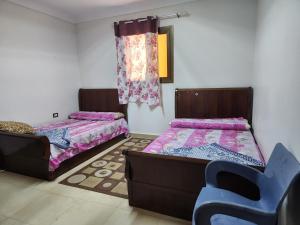 een kamer met 2 bedden en een stoel. bij شقة مصيف الاسكندرية - البيطاش بيانكي in Alexandrië