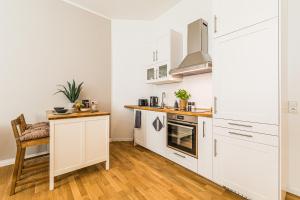 a kitchen with white cabinets and a wooden floor at Luxury Style 2 Room Apartment by R&L in Centre in Leipzig