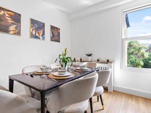 a dining room with a table and white chairs at Chelsea Maisonette in London