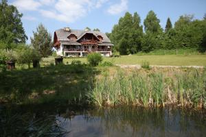 an old house sitting next to a body of water at Siedlisko Brzeziniak in Cisna