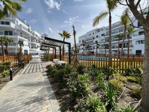 una passerella di fronte a un edificio con palme di PUSHE Playa Granada Beach & Golf 15 a Motril
