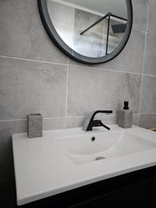 ein weißes Waschbecken mit einem Spiegel an der Wand in der Unterkunft Le B96 in Cayenne