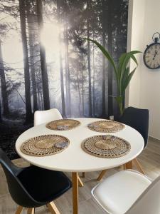 a white table with four chairs and a forest mural at La Lunita in Valverde