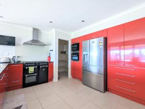 a kitchen with red cabinets and a stainless steel refrigerator at Luxury Lake View farm stay with spa pool in Rotorua