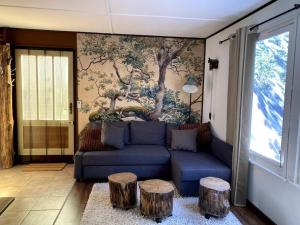 a living room with a blue couch and two tree stools at Gästehaus Zur Walnuss Berlin in Blankenfelde