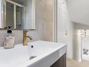 a white bathroom with a sink and a mirror at Chelsea Maisonette in London