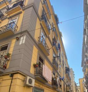 un edificio alto de color amarillo con balcones y ventanas en RUMA GUESTHOUSE, en Nápoles