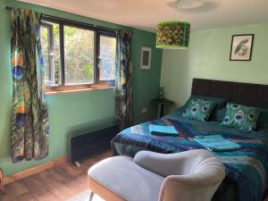 1 dormitorio con 1 cama, 1 silla y ventanas en The Bird House, en Narberth