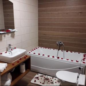 a bathroom with a tub and a toilet and a sink at Hotel Rafaelo in Bosanska Dubica