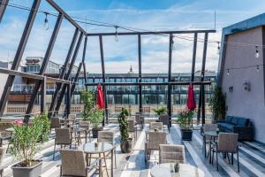 eine Terrasse mit Tischen und Stühlen und Stadtblick in der Unterkunft Ramada by Wyndham Budapest City Center in Budapest