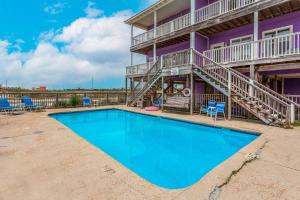 a swimming pool in front of a purple house with blue chairs at Purple House East and West in Fort Morgan