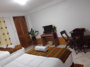 a living room with a bed and a desk with a television at Incas Town Inn in Cusco