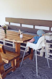 a child sitting in a chair at a picnic table at Chalúpka na konci in Banská Štiavnica