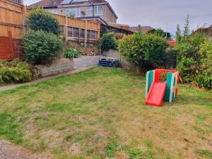 a yard with two play equipment in the grass at Fabulous family house next to the beach in Nottage