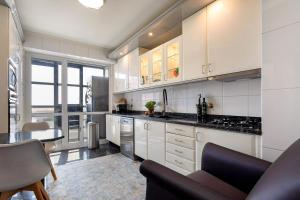 a kitchen with white cabinets and a black counter top at Oporto, sea view and marina in Canidelo
