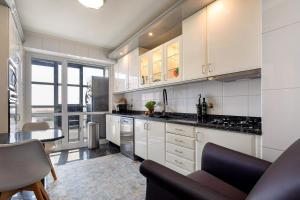 a kitchen with white cabinets and a black counter top at Oporto, sea view and marina in Canidelo