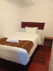 a bedroom with a large white bed with a striped headboard at Incas Town Inn in Cusco