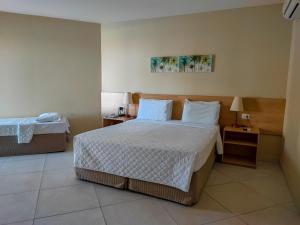 a hotel room with a bed and two night stands at Hotel Coral Beach in Tamandaré