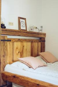 łóżko z drewnianym zagłówkiem i zegarem na ścianie w obiekcie Chalúpka na konci w Bańskiej Szczawnicy